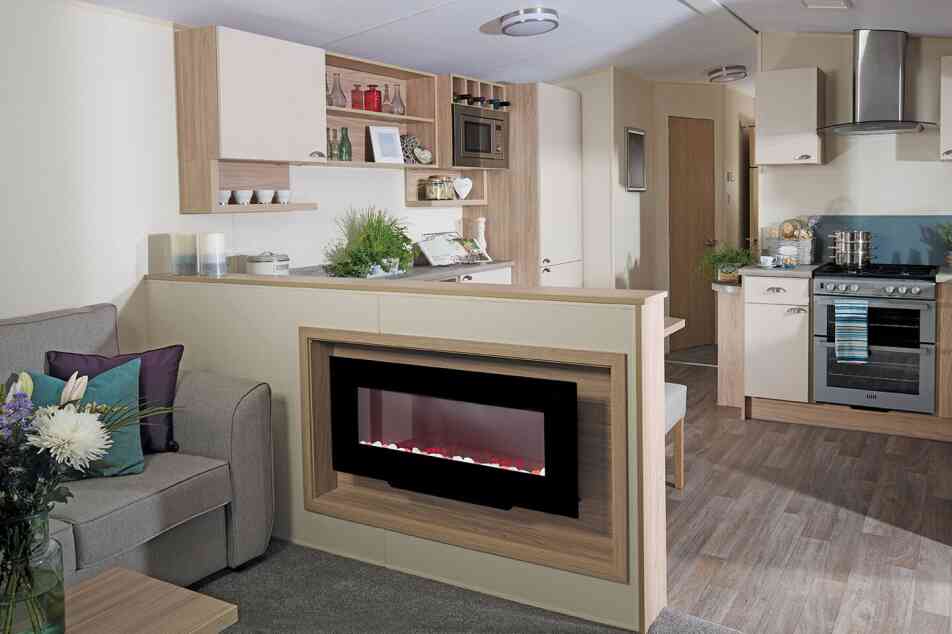 A stylish living room with a couch, connected kitchen, and a fireplace, designed for comfort and socializing.