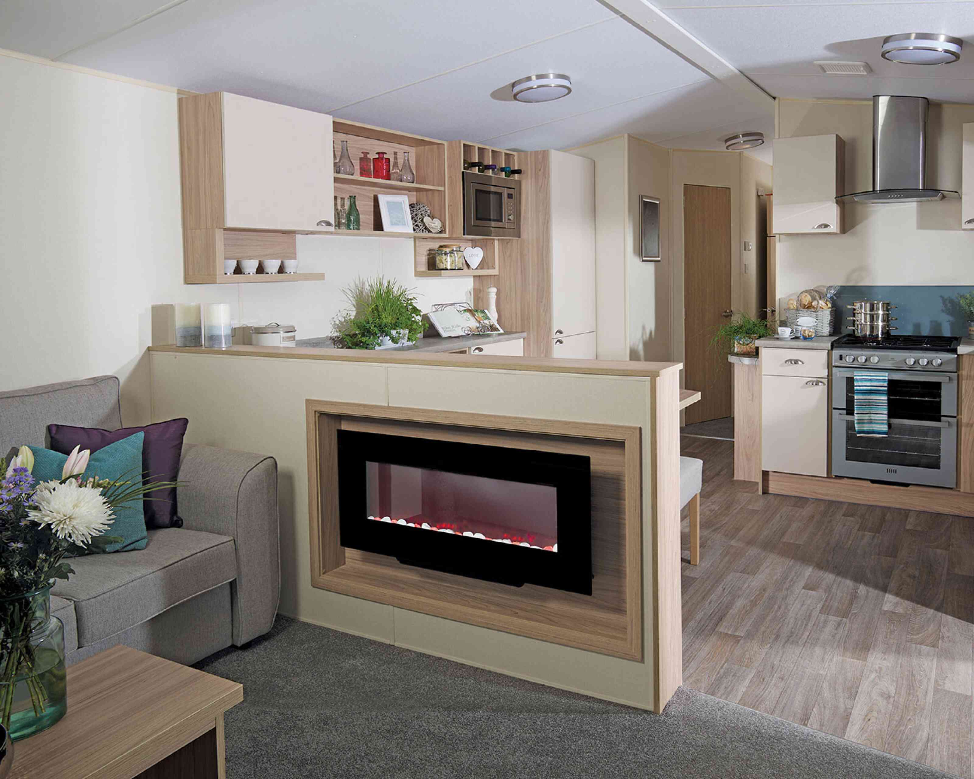 A stylish living room with a couch, connected kitchen, and a fireplace, designed for comfort and socializing.