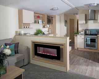 A stylish living room with a couch, connected kitchen, and a fireplace, designed for comfort and socializing.