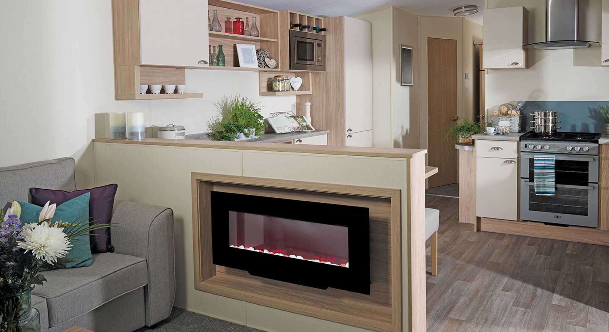 A stylish living room with a couch, connected kitchen, and a fireplace, designed for comfort and socializing.