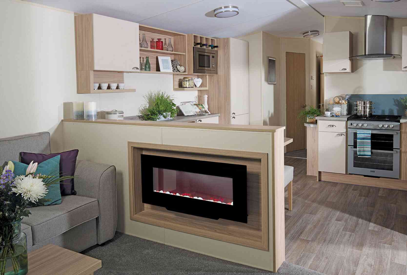 A stylish living room with a couch, connected kitchen, and a fireplace, designed for comfort and socializing.