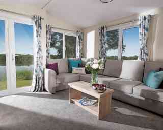 A cosy living room featuring a couch, coffee table, and a large window letting in natural light.