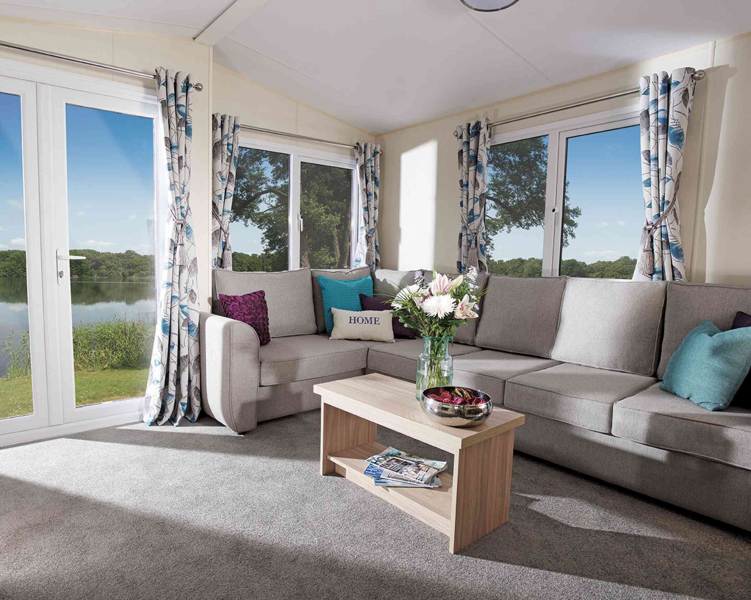 A cosy living room featuring a couch, coffee table, and a large window letting in natural light.