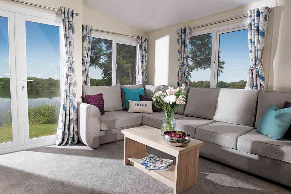 A cosy living room featuring a couch, coffee table, and a large window letting in natural light.