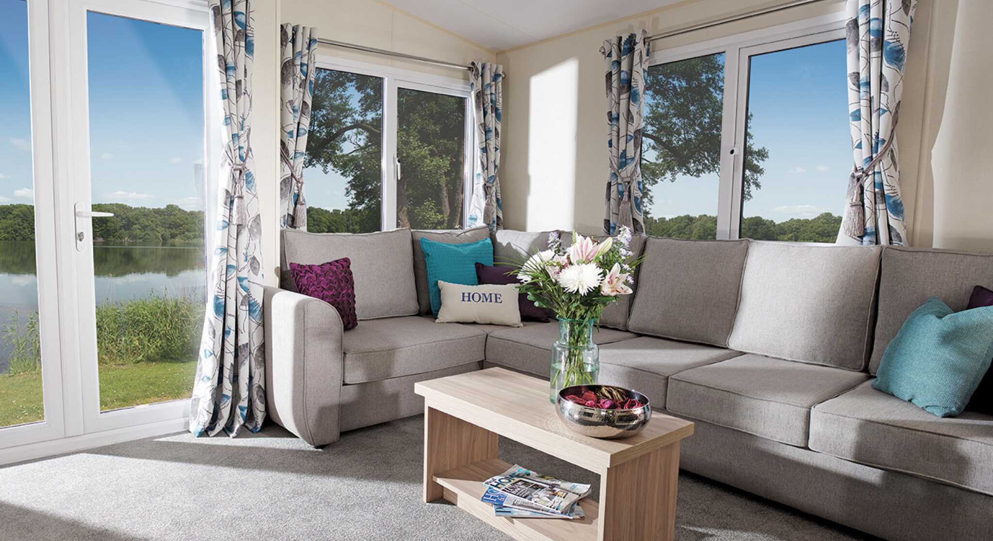 A cosy living room featuring a couch, coffee table, and a large window letting in natural light.