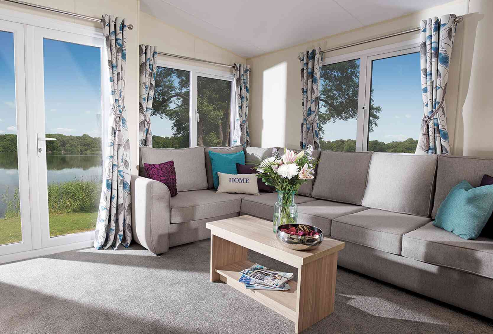A cosy living room featuring a couch, coffee table, and a large window letting in natural light.