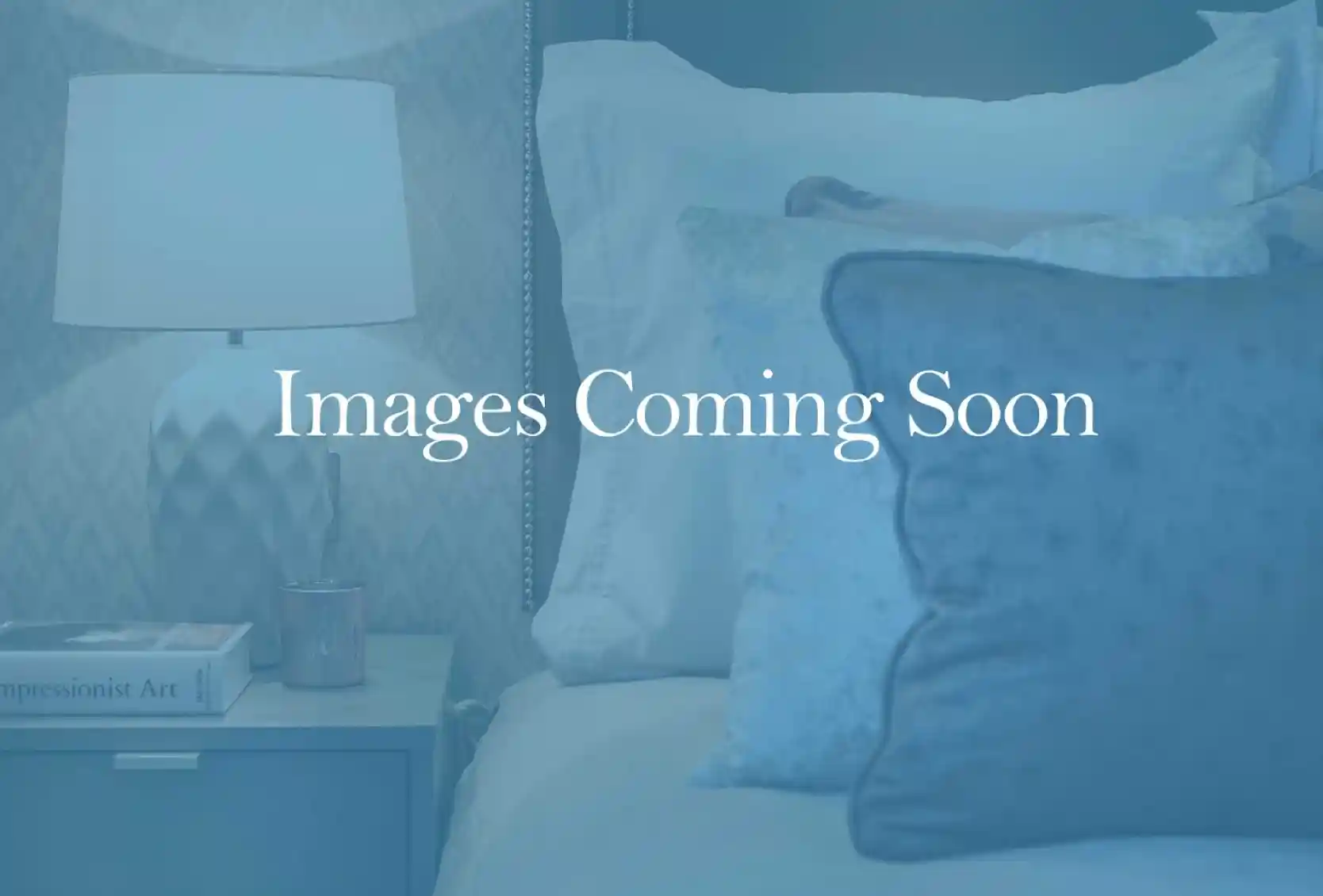 A cozy bedroom scene featuring a neatly made bed with plush pillows and a bedside table topped with a decorative lamp and a small candle. The background suggests a calming ambiance.