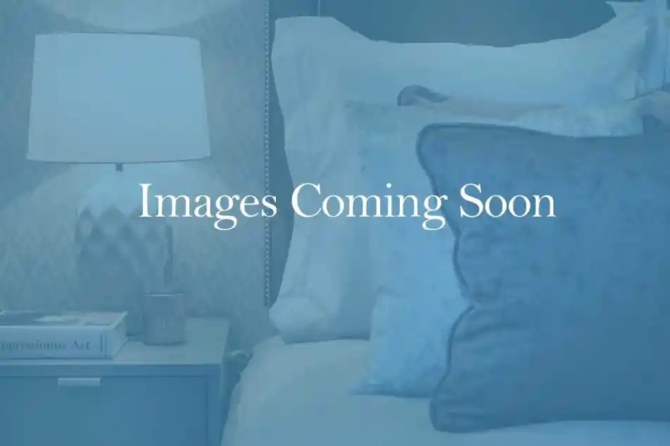 A cozy bedroom scene featuring a neatly made bed with plush pillows and a bedside table topped with a decorative lamp and a small candle. The background suggests a calming ambiance.