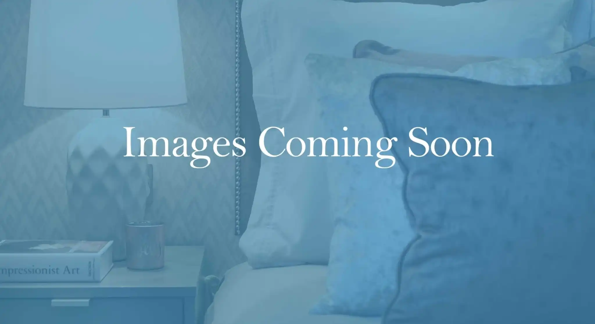 A cozy bedroom scene featuring a neatly made bed with plush pillows and a bedside table topped with a decorative lamp and a small candle. The background suggests a calming ambiance.