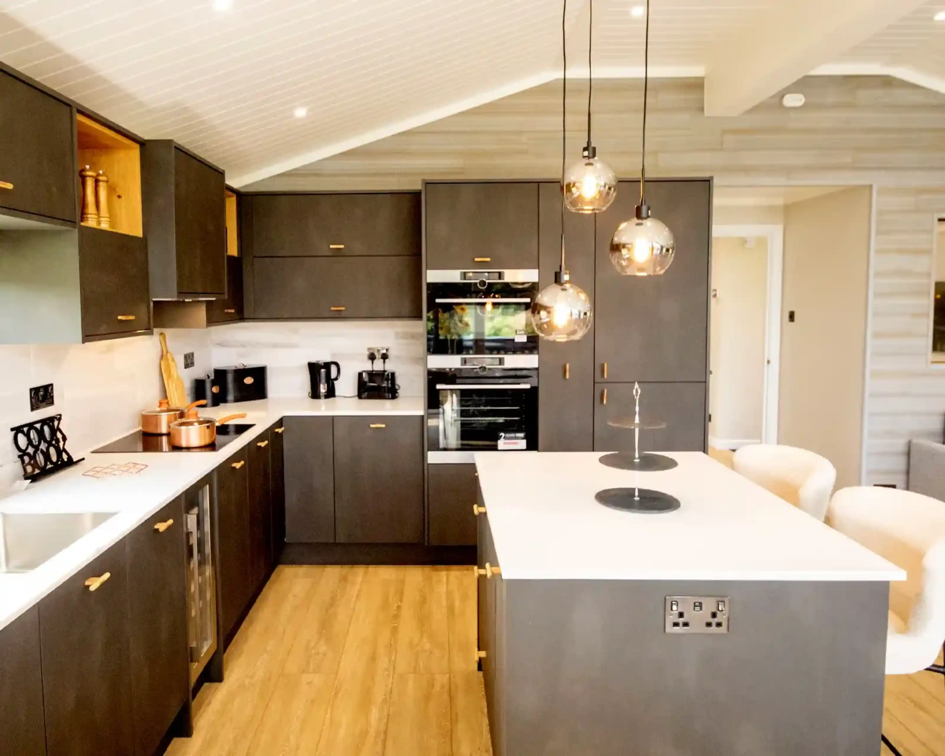 Modern grey kitchen with dark cabinetry, a white island, and pendant lighting.