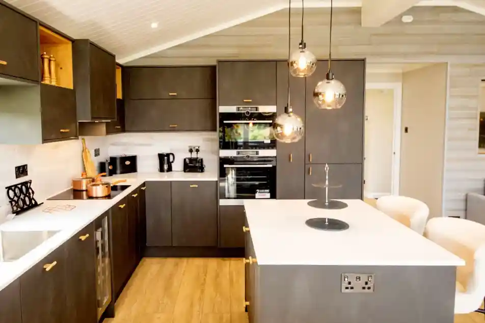 Modern grey kitchen with dark cabinetry, a white island, and pendant lighting.