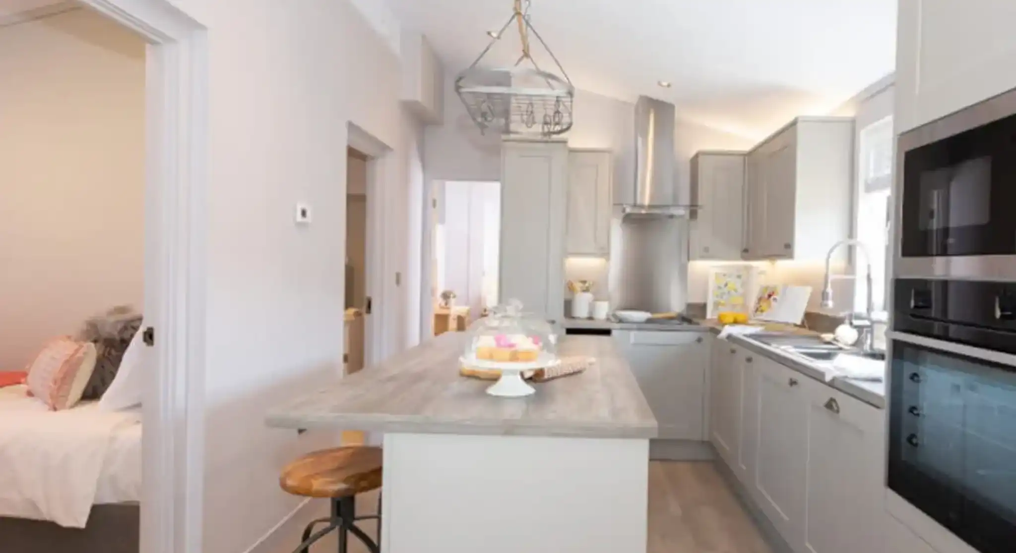 Modern, light-filled kitchen with a breakfast bar and a view into a bedroom.