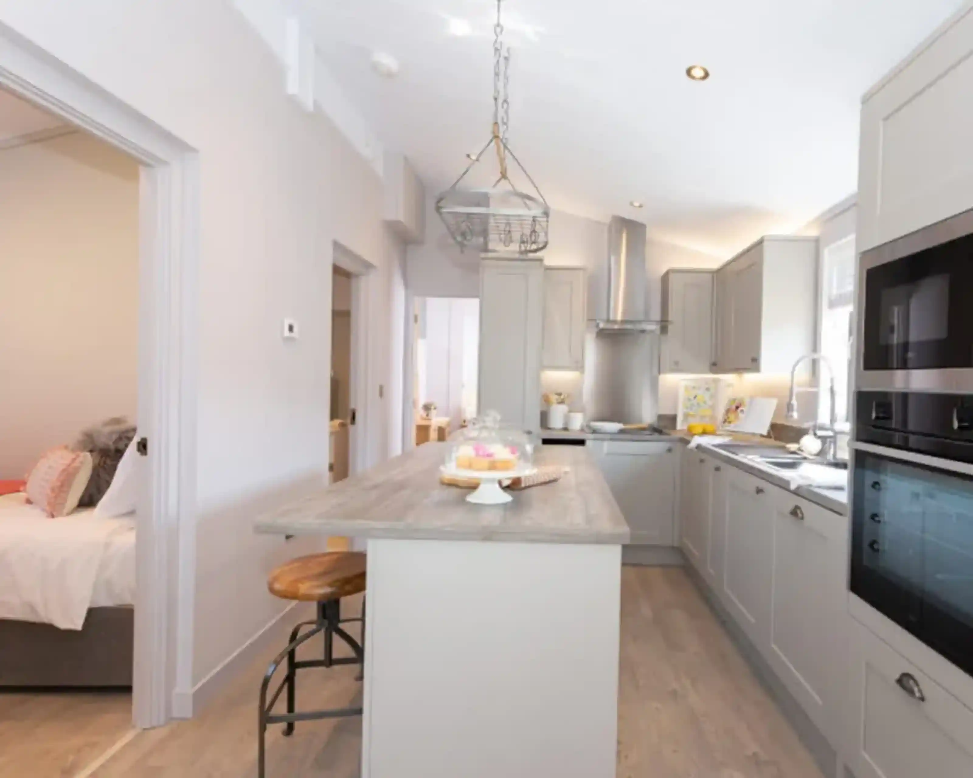 Modern, light-filled kitchen with a breakfast bar and a view into a bedroom.