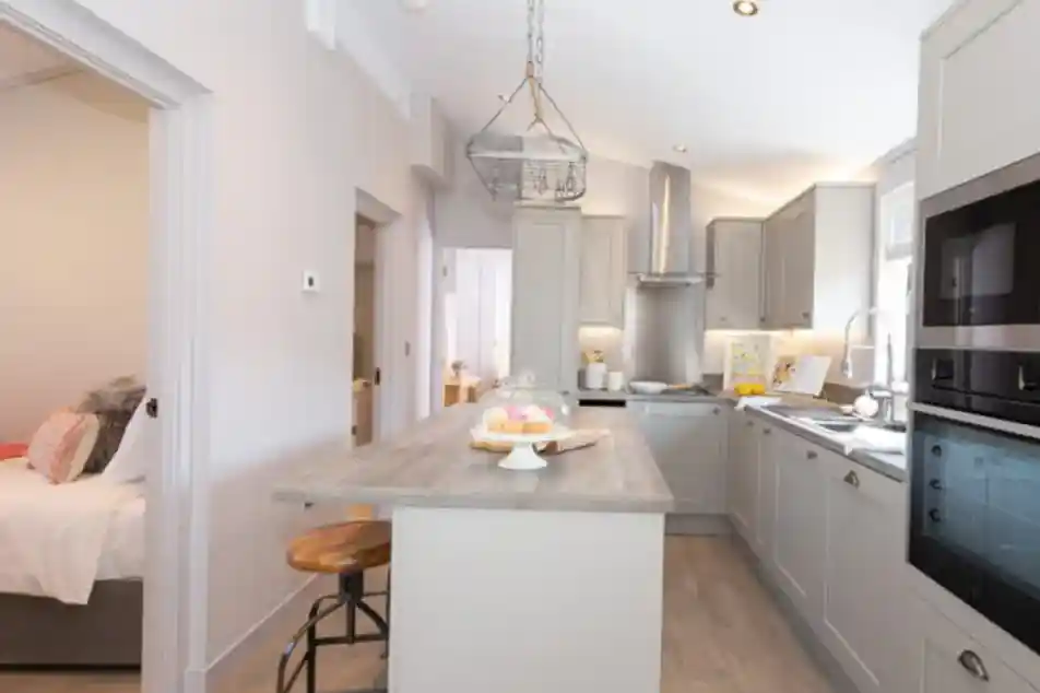 Modern, light-filled kitchen with a breakfast bar and a view into a bedroom.