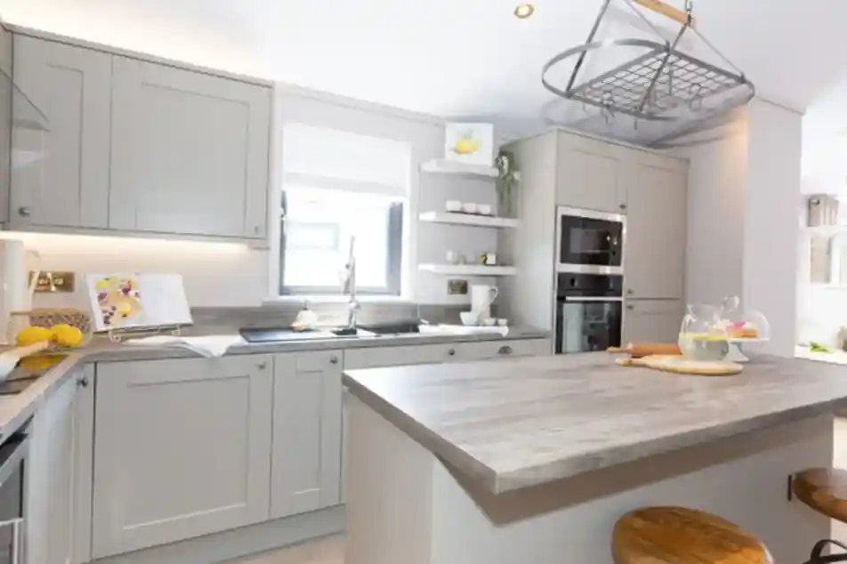 Modern grey kitchen with a central island, stainless steel appliances, and a hanging pot rack.