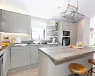 Modern grey kitchen with a central island, stainless steel appliances, and a hanging pot rack.