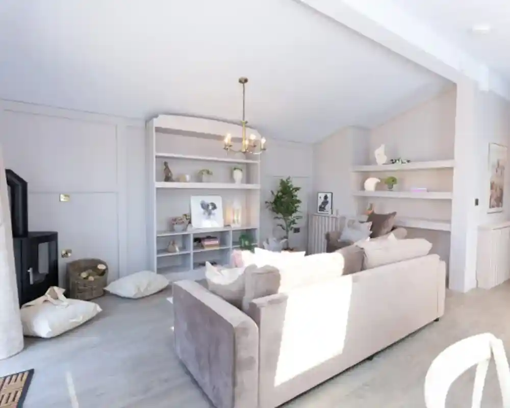 A bright, modern living room features a plush sofa, a black wood-burning stove, and built-in shelves displaying décor.