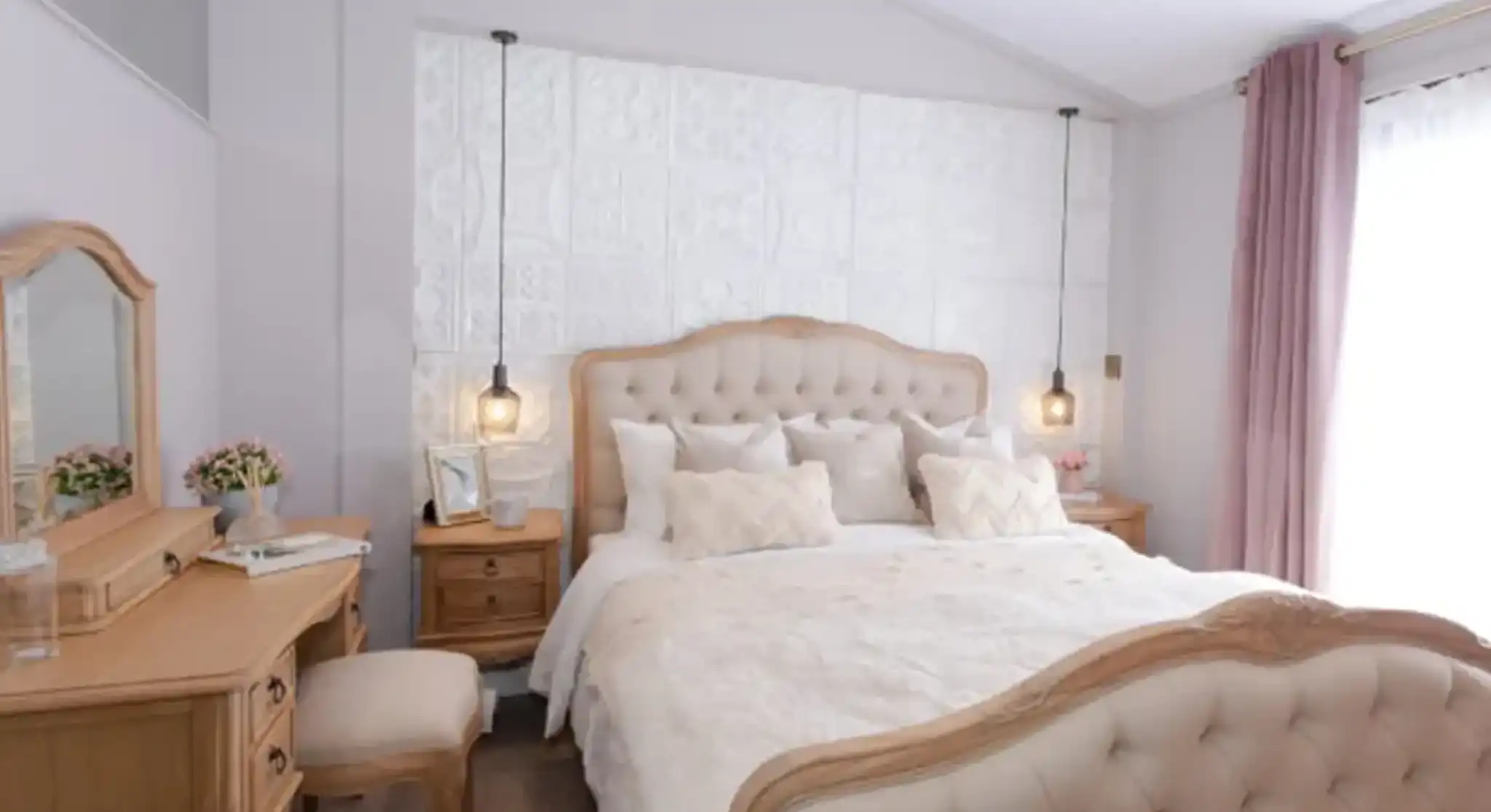 Elegant bedroom with a tufted cream bed, wooden vanity, and plush pink curtains.