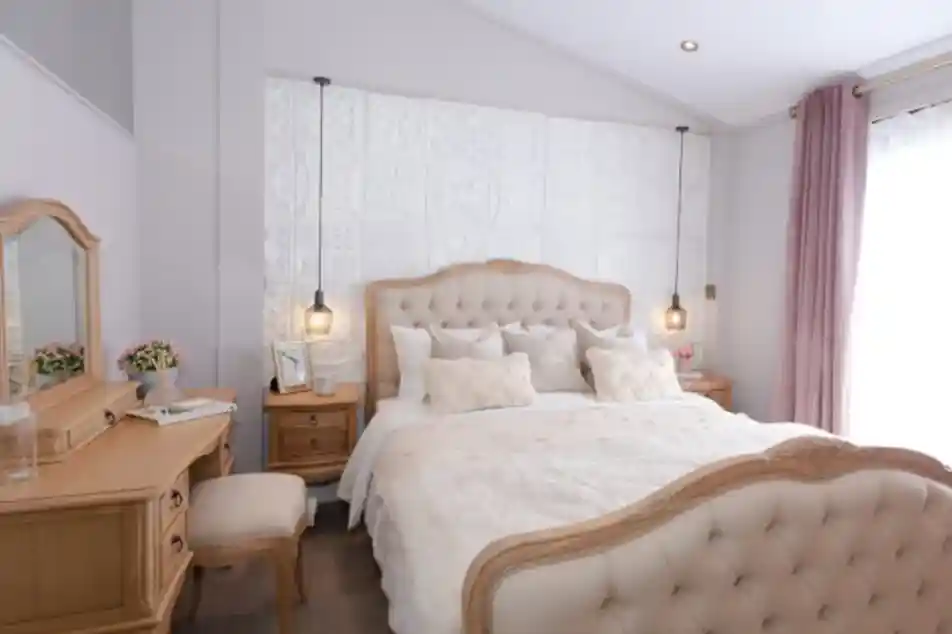 Elegant bedroom with a tufted cream bed, wooden vanity, and plush pink curtains.