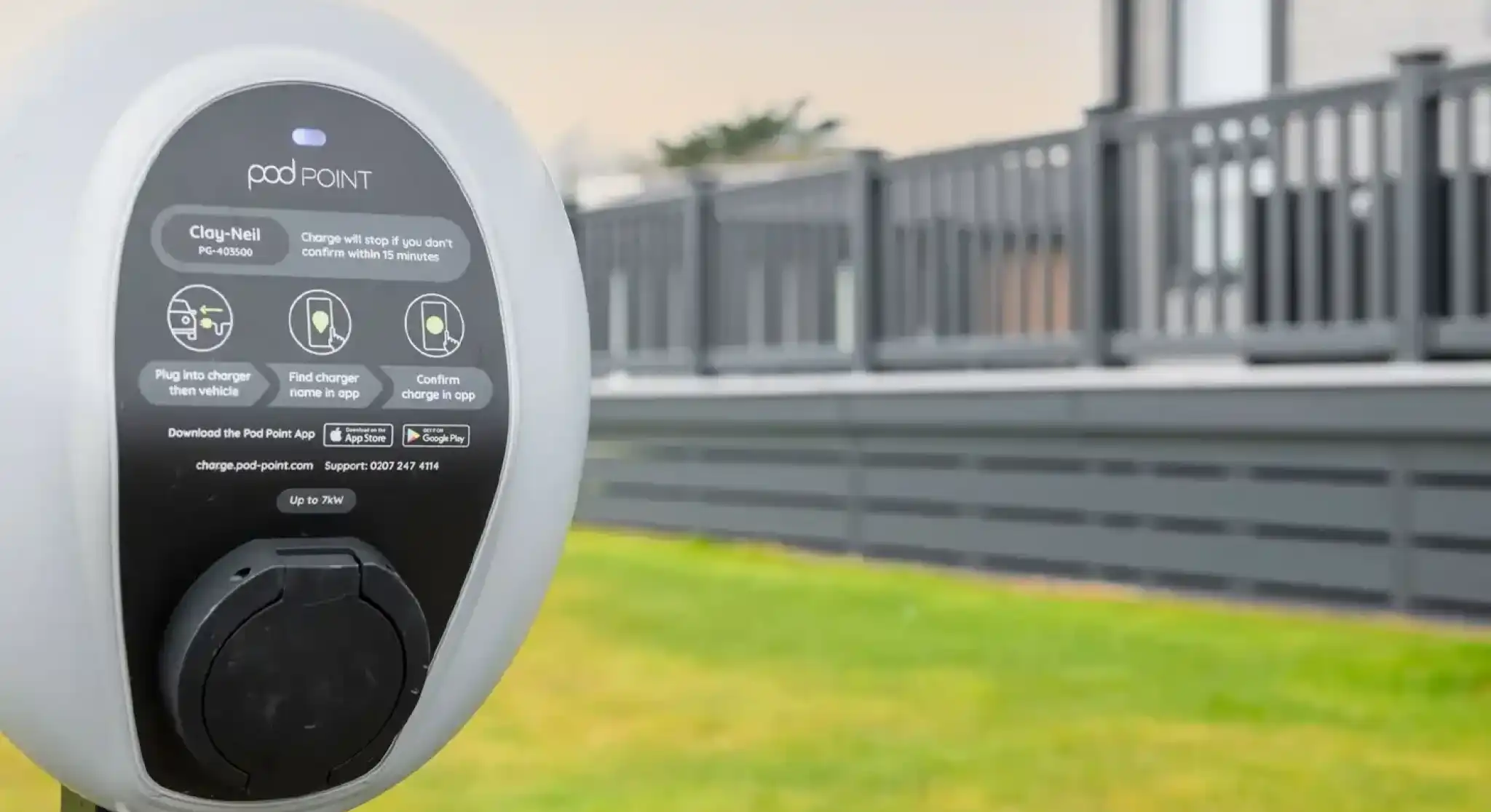 Pod Point electric car charger in front of a grey clad lodge holiday home with decking.