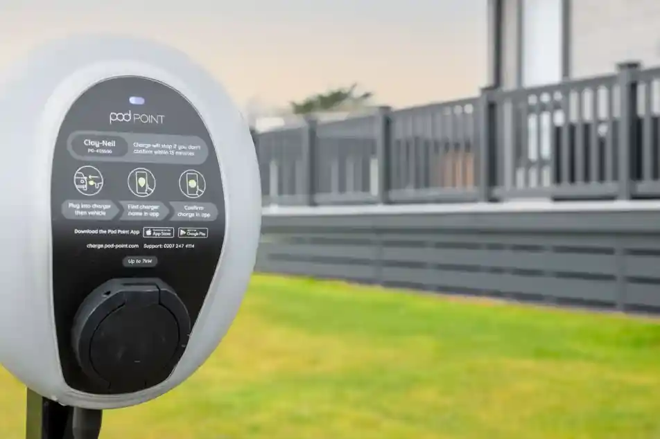 Pod Point electric car charger in front of a grey clad lodge holiday home with decking.