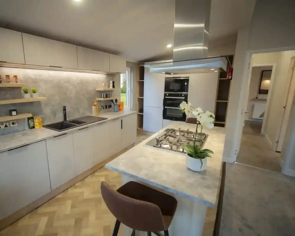 Modern kitchen featuring minimalist white cabinets, a marble countertop, and a built-in oven, illuminated by natural and recessed lighting.