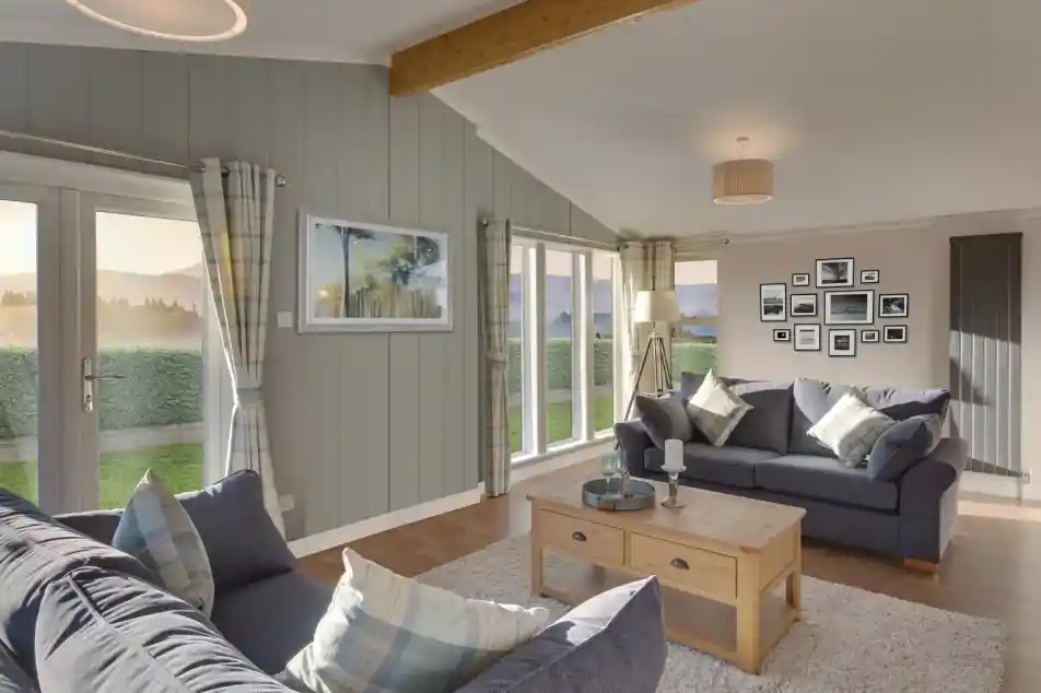 Spacious living room with vaulted ceiling, grey sofas, and large windows offering scenic views.