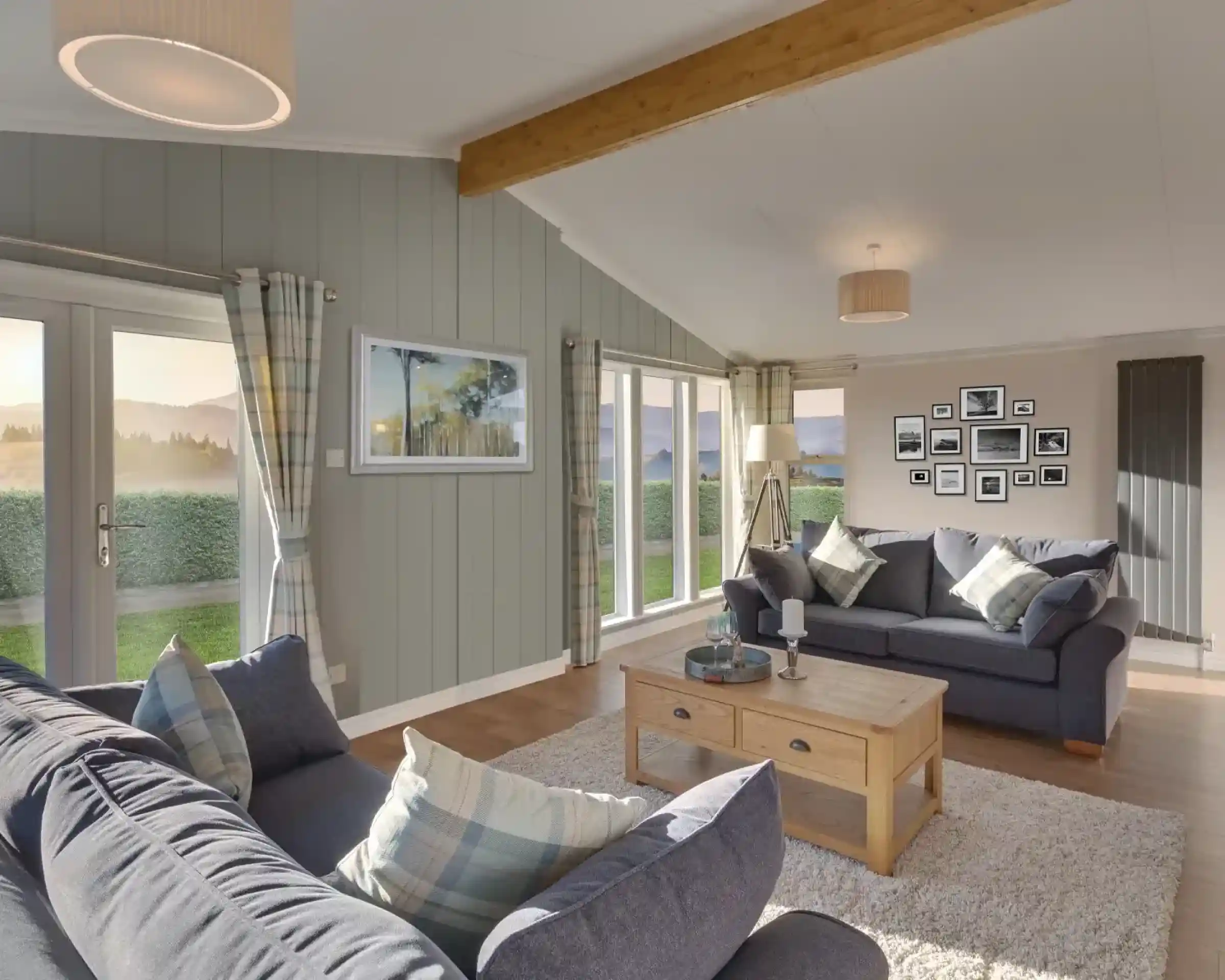 Spacious living room with vaulted ceiling, grey sofas, and large windows offering scenic views.