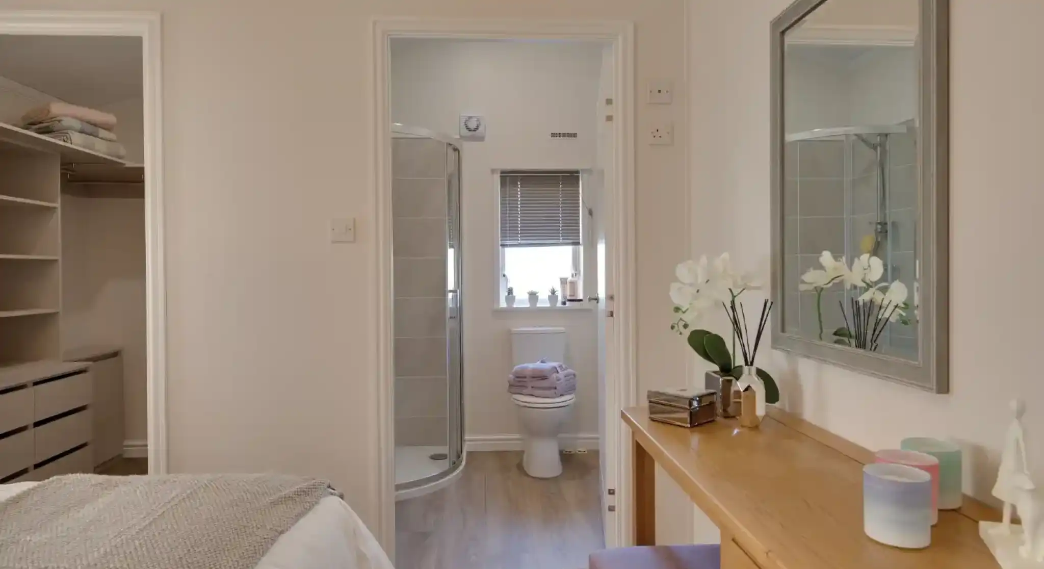 Bedroom with an open doorway to a bathroom with a toilet and shower, and a vanity with a mirror.