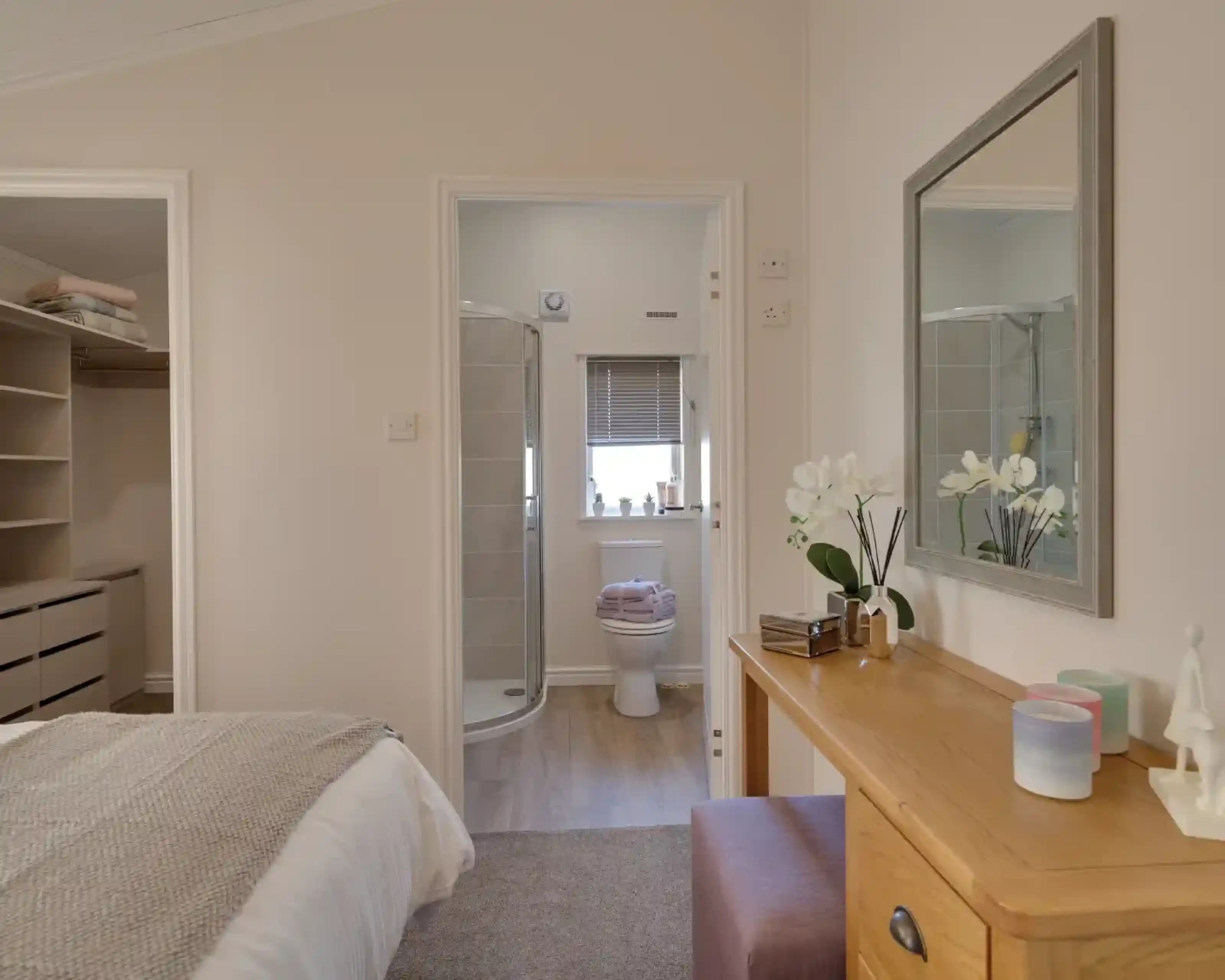Bedroom with an open doorway to a bathroom with a toilet and shower, and a vanity with a mirror.