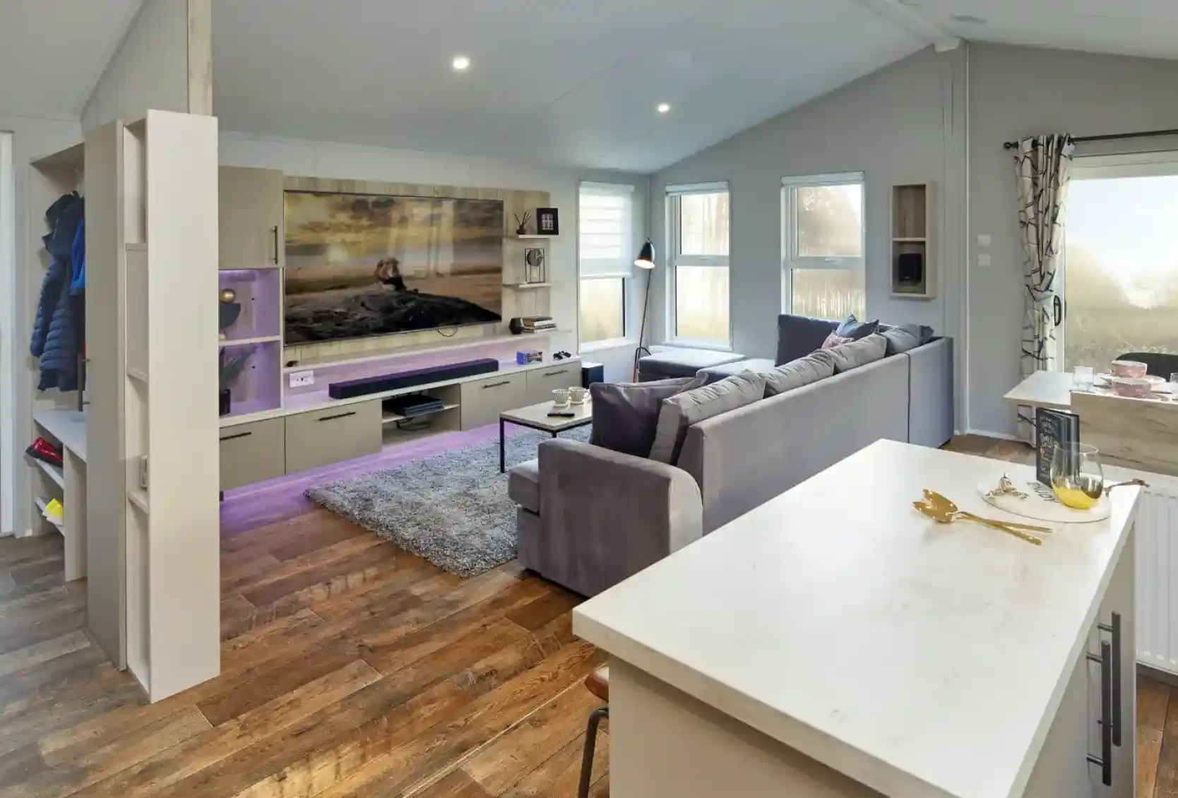 Modern living room with large sectional sofa, entertainment centre, and island breakfast bar.