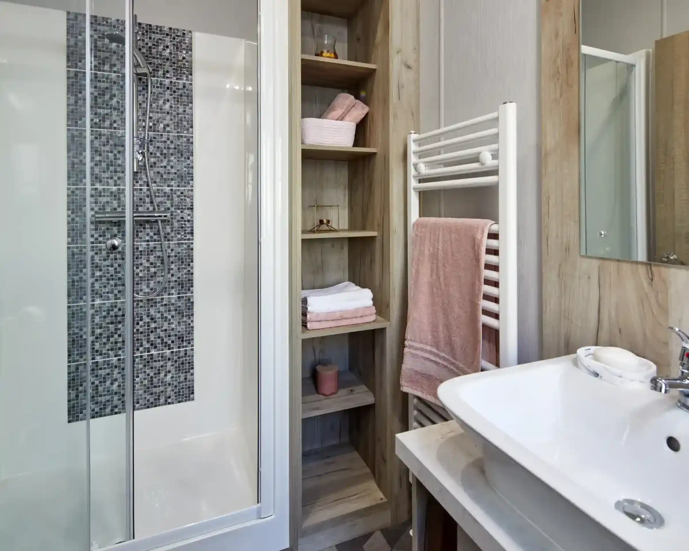 Modern bathroom with a glass-enclosed shower, open shelving, and a white sink with a towel rack.