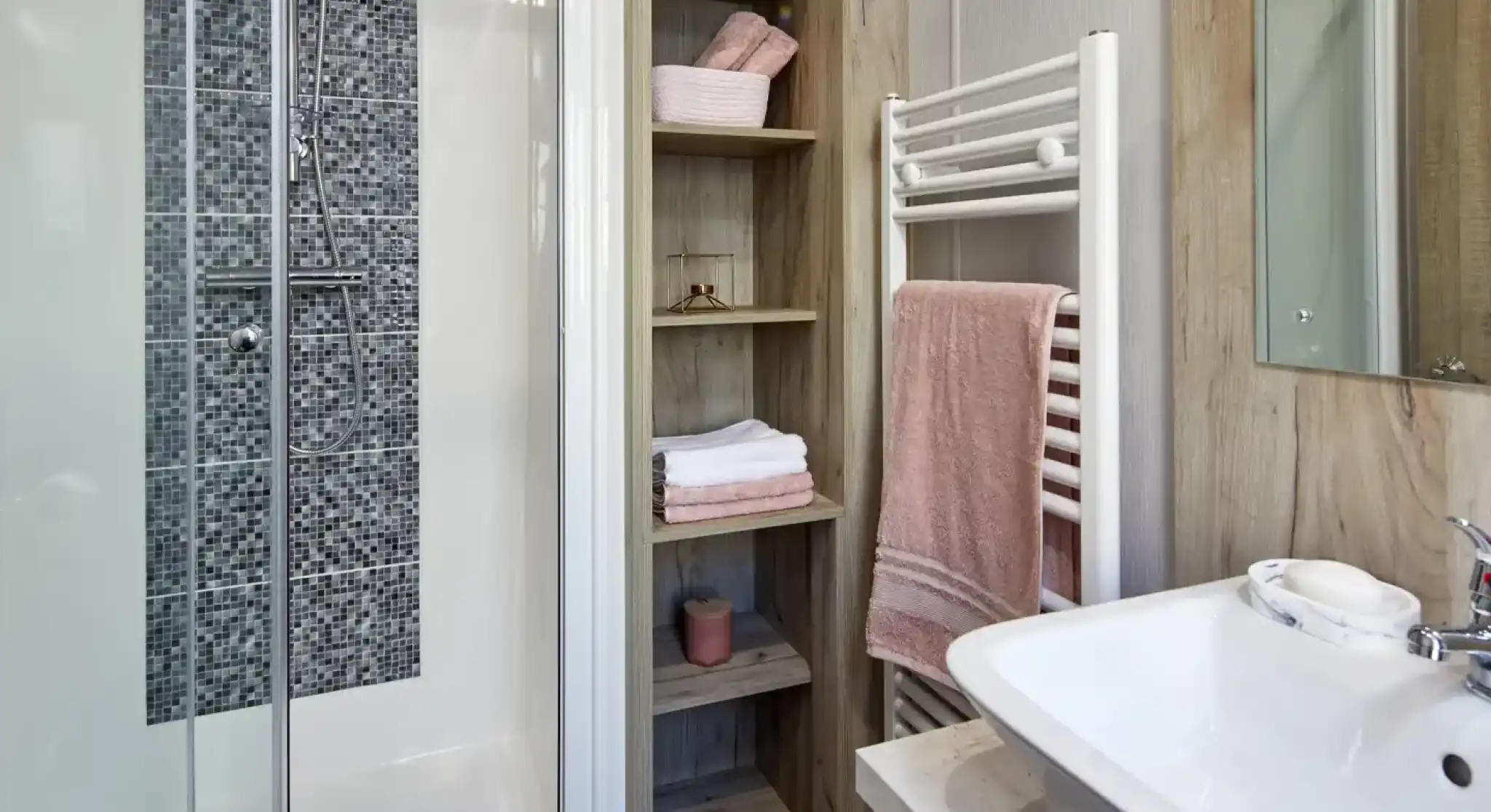 Modern bathroom with a glass-enclosed shower, open shelving, and a white sink with a towel rack.