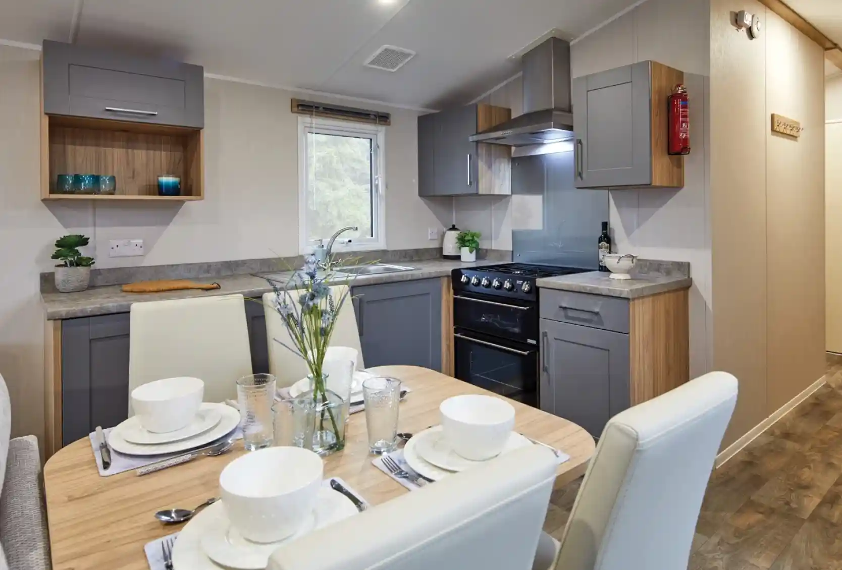 Modern kitchen and dining area in a holiday caravan with grey and wood cabinetry, set dining table, and a warm, contemporary design.