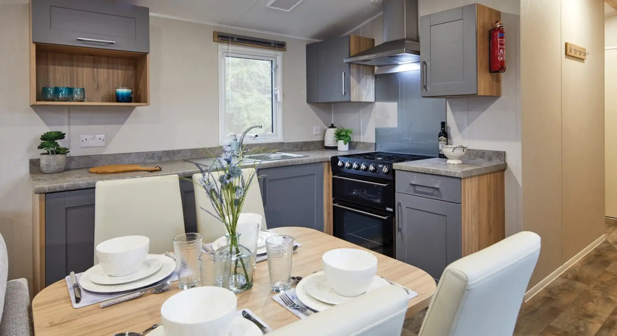 Modern kitchen and dining area in a holiday caravan with grey and wood cabinetry, set dining table, and a warm, contemporary design.