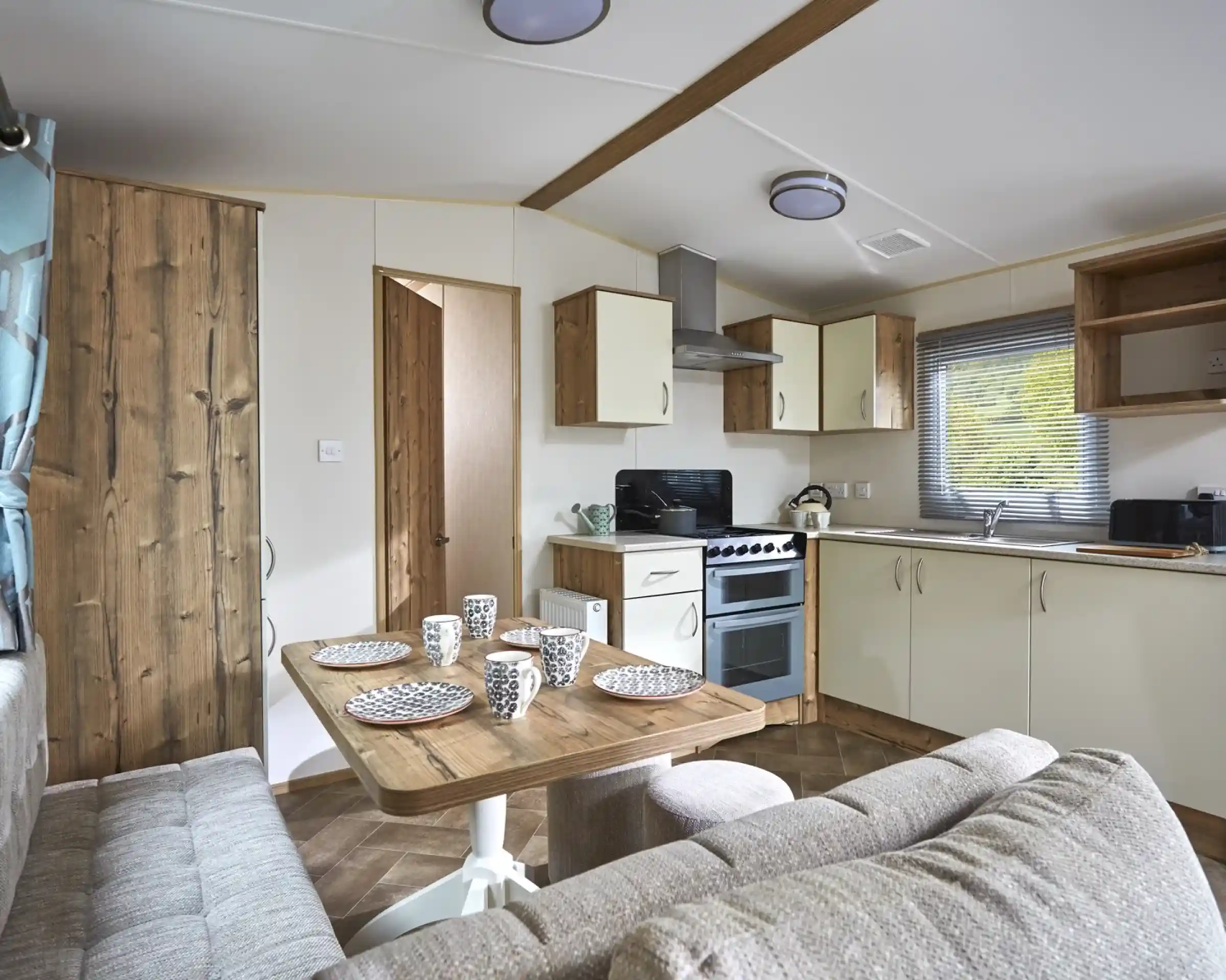 Modern mobile home kitchen and dining area with a sofa and table set for four.