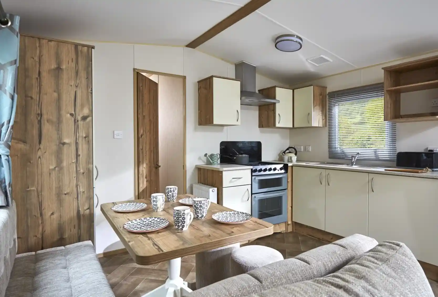 Modern mobile home kitchen and dining area with a sofa and table set for four.