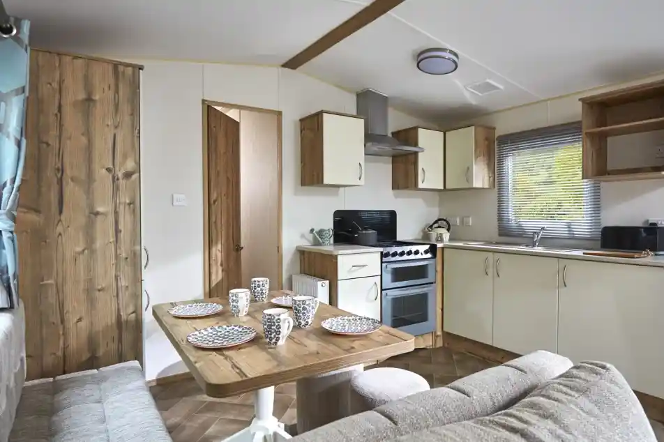 Modern mobile home kitchen and dining area with a sofa and table set for four.