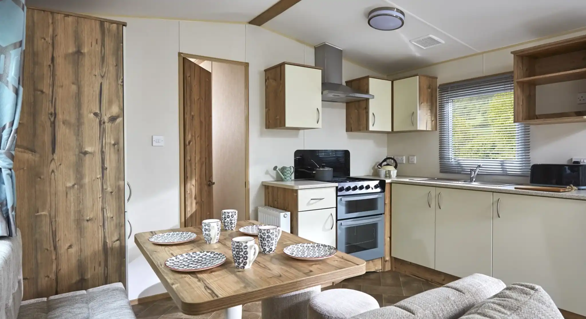 Modern mobile home kitchen and dining area with a sofa and table set for four.