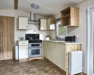 A modern caravan kitchen with cream cabinets, a double oven, and wooden accents.