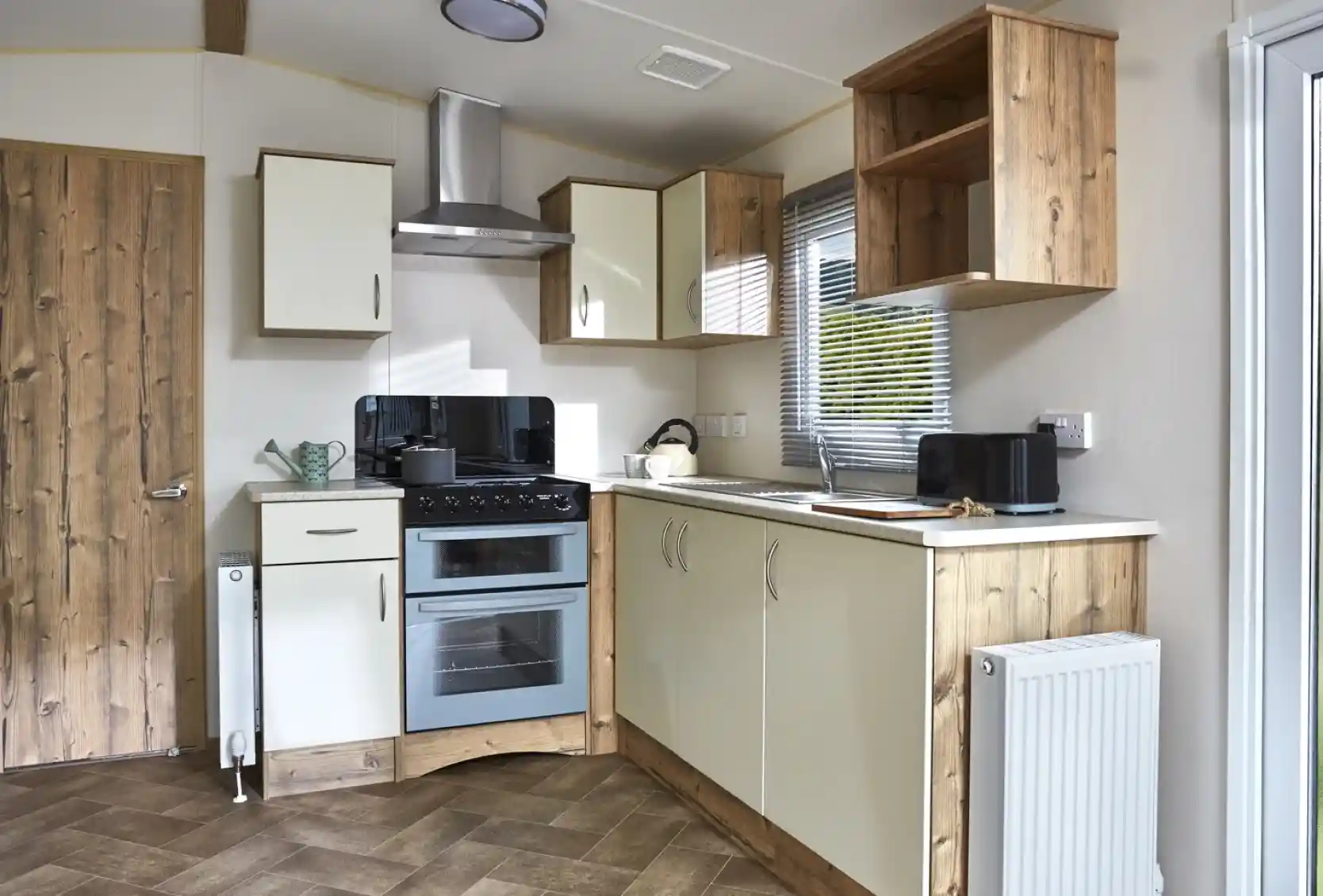A modern caravan kitchen with cream cabinets, a double oven, and wooden accents.