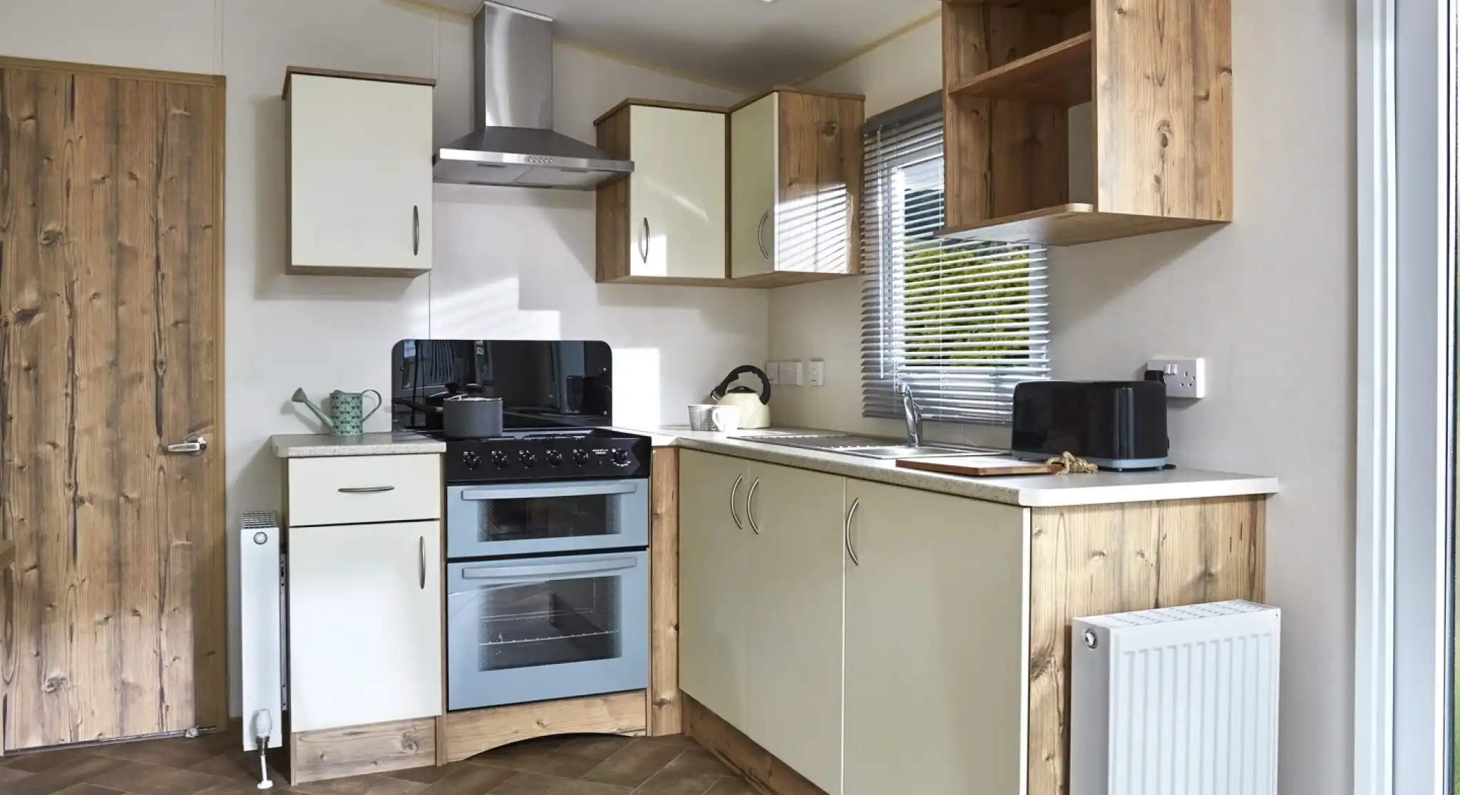 A modern caravan kitchen with cream cabinets, a double oven, and wooden accents.