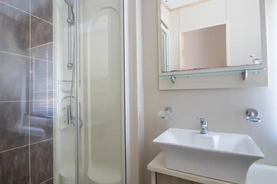 A modern bathroom featuring a glass shower stall, a stylish sink with a sleek faucet, and minimalistic wall decor. Natural light filters through a window.