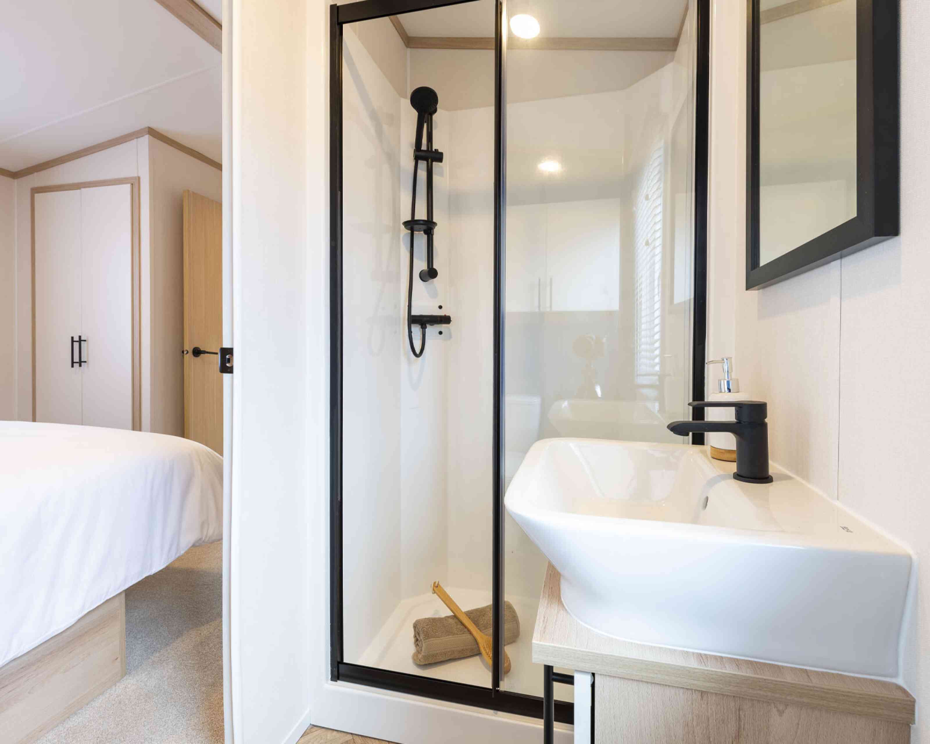 A well-lit en suite bathroom with a stylish shower enclosure and a minimalist sink, designed with neutral tones and elegant finishes.