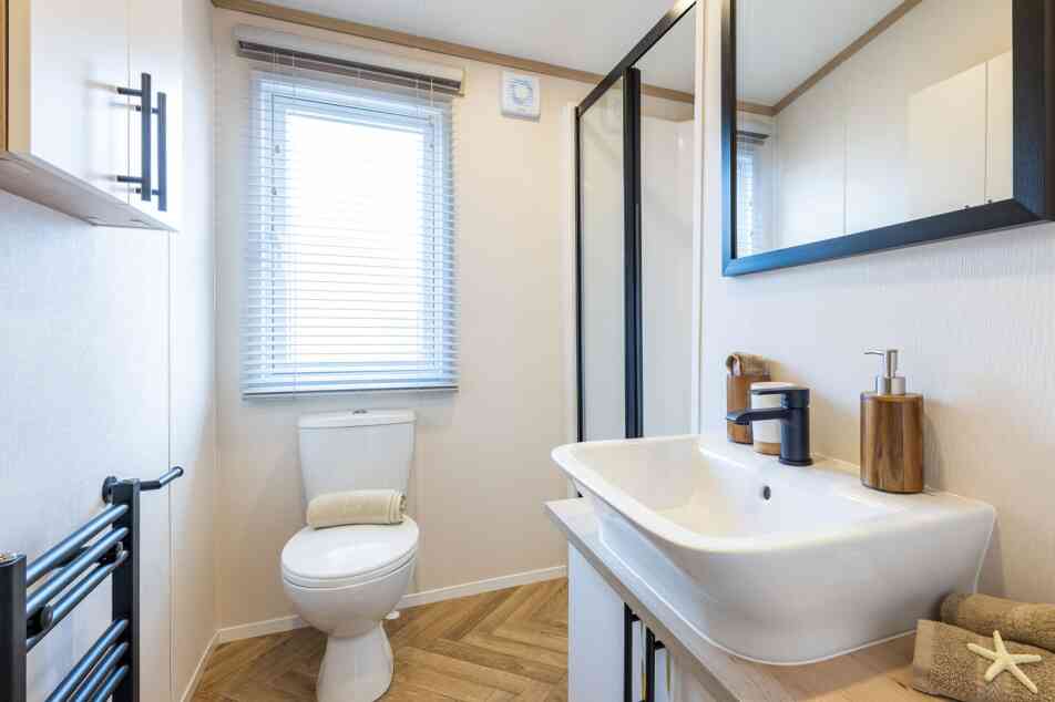 A modern bathroom showcasing a sink, toilet, shower enclosure and a mirror, all arranged neatly in a well-lit environment.