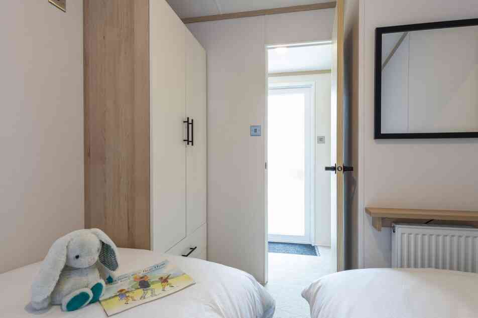 A twin bedroom with twin single beds and space for a tall wardrobe in one corner.