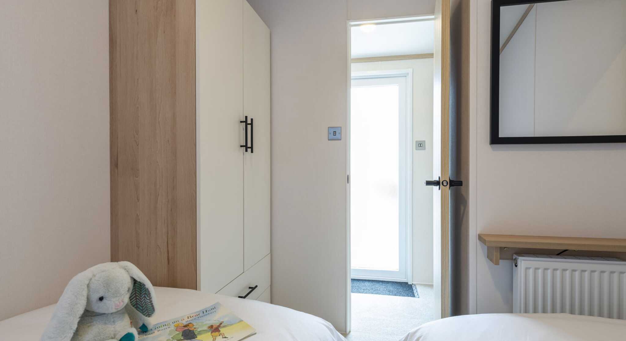 A twin bedroom with twin single beds and space for a tall wardrobe in one corner.