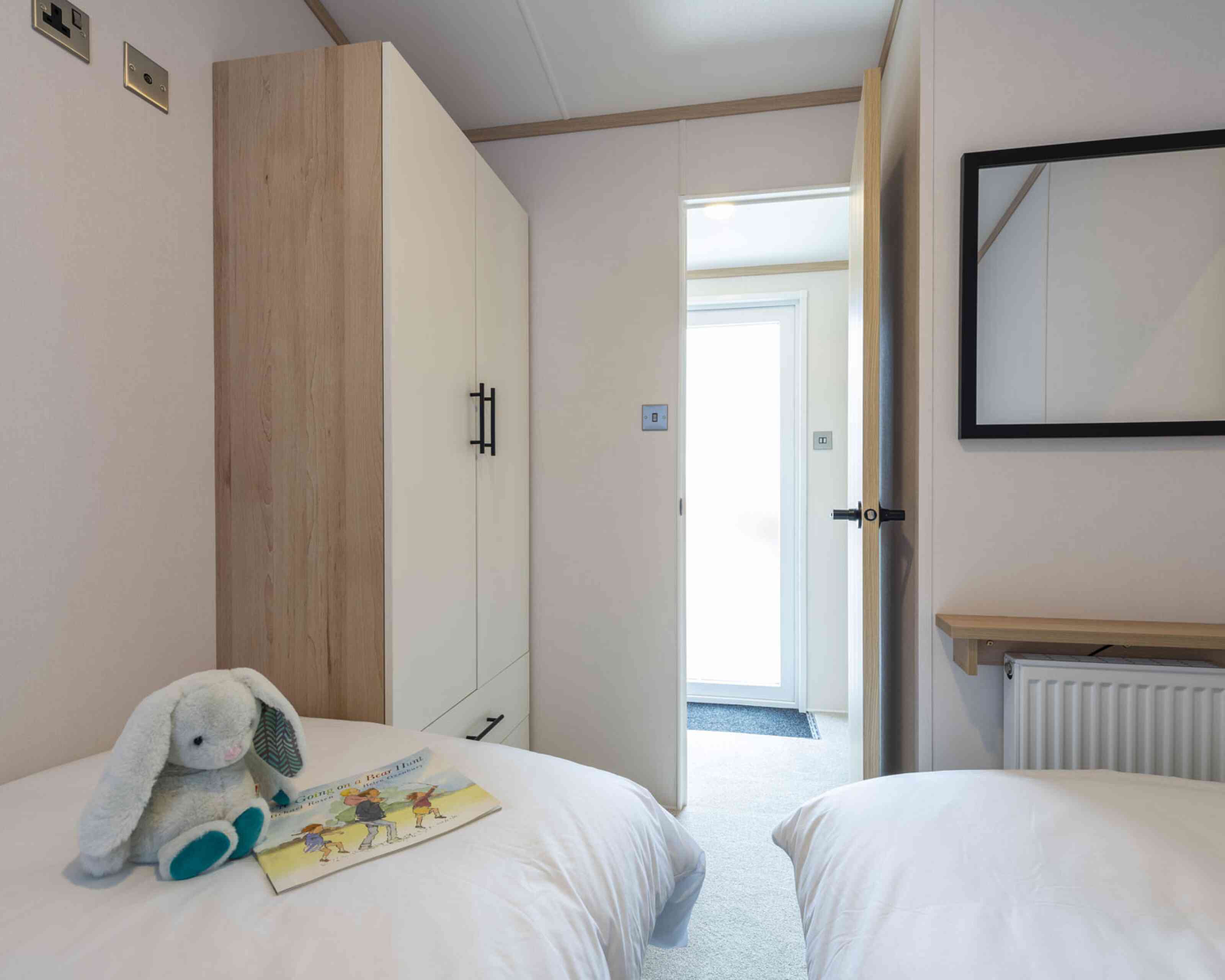 A twin bedroom with twin single beds and space for a tall wardrobe in one corner.