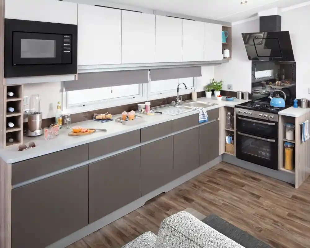 Modern kitchen with white and grey cabinets, stainless steel appliances, and hardwood floors.
