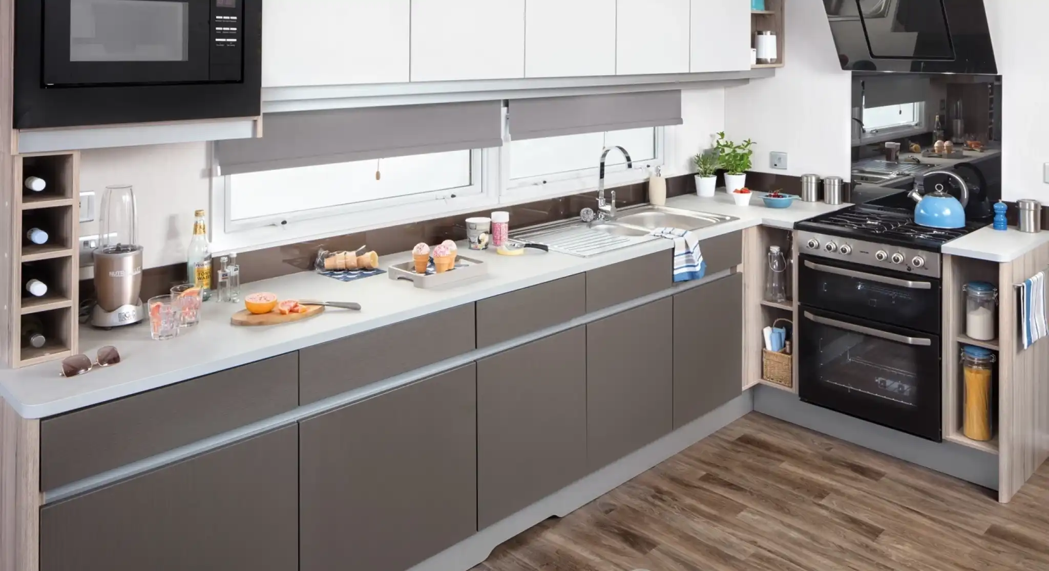 Modern kitchen with white and grey cabinets, stainless steel appliances, and hardwood floors.